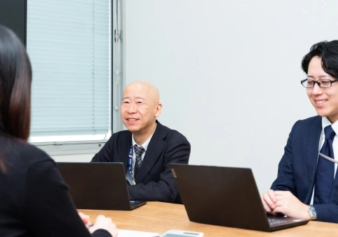 会議室でスタッフ同士が笑顔で話し合う様子