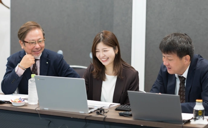 3人がノートPCを前に笑顔で打ち合わせをしている様子