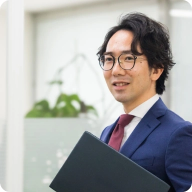 ノートPCを手に微笑むスーツ姿の男性スタッフ