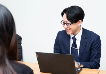 スタッフが対面の人物に向かって笑顔で話している様子