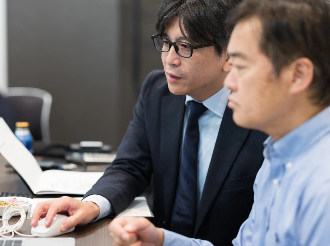 スタッフが隣の人物にノートPCを見せながら説明している様子