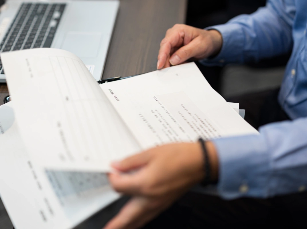 ノートPCの前で資料を手に取り確認しているクローズアップ